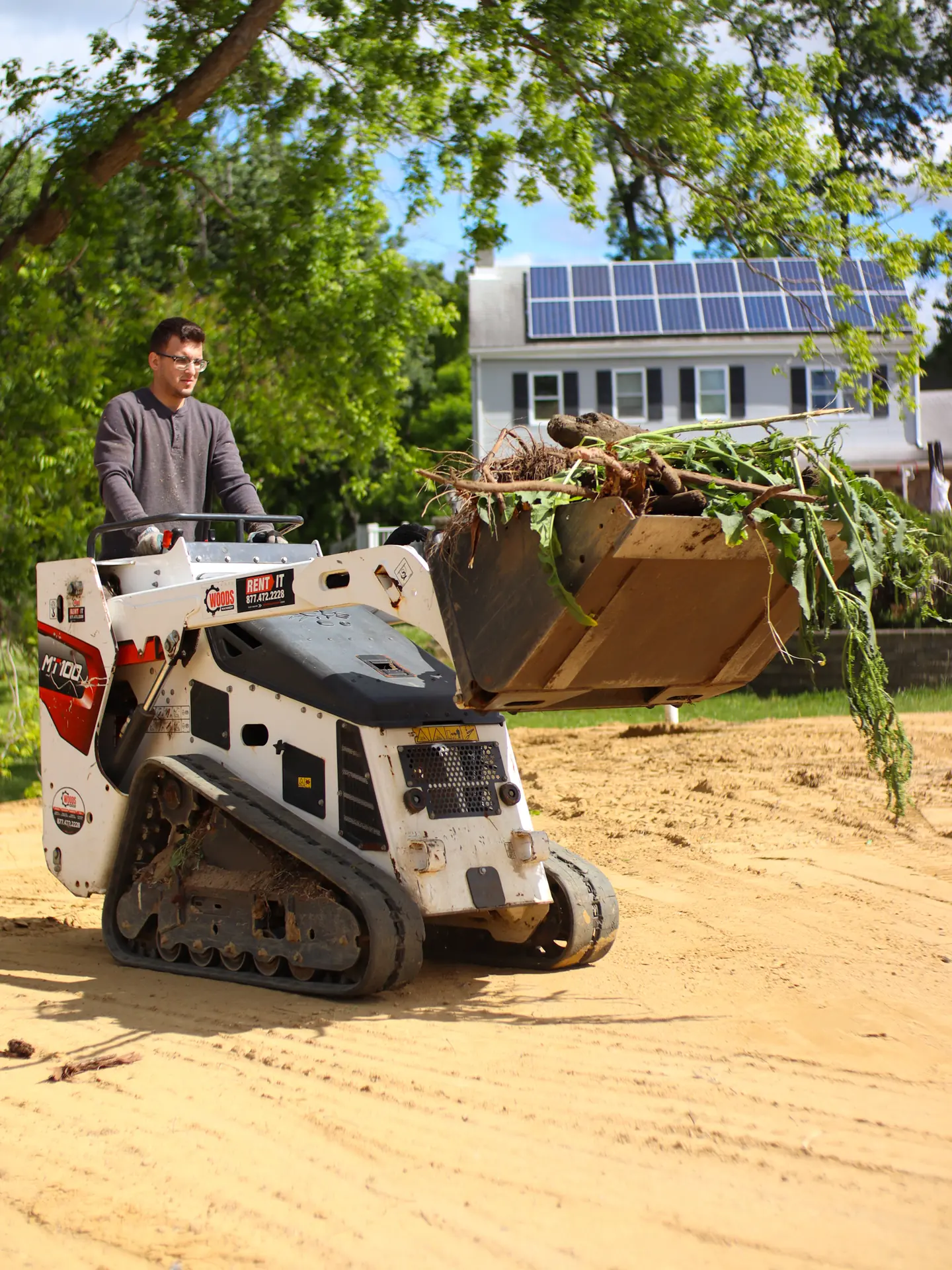 A Lawns by Rainey operator clearing brush with a track loader on a new build lot
