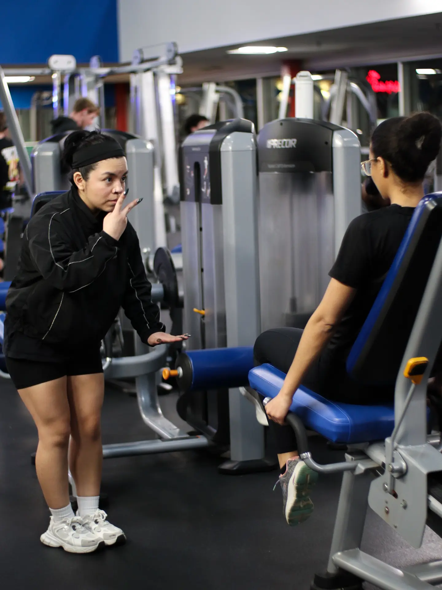 A PowerHaus Fitness trainer coaching a client through a set on the gym floor
