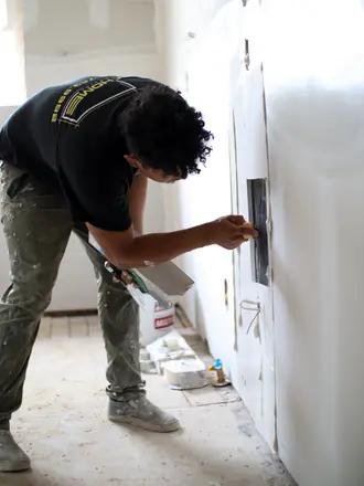 AZ Home Remodeling installer patching drywall around an outlet box