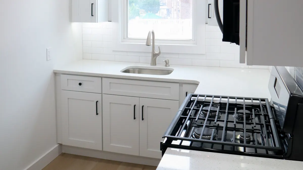 A finished AZ Home Remodeling kitchen: white shaker cabinets, quartz counters and a black gas range