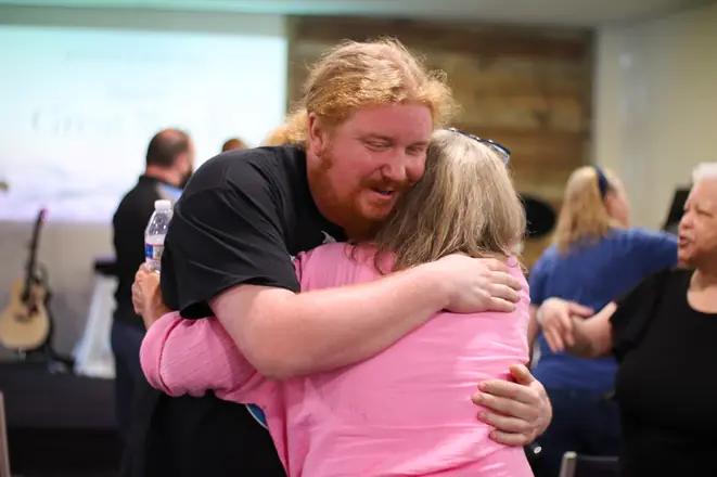 Two Matheteuo Ministries members sharing a warm hug after a service