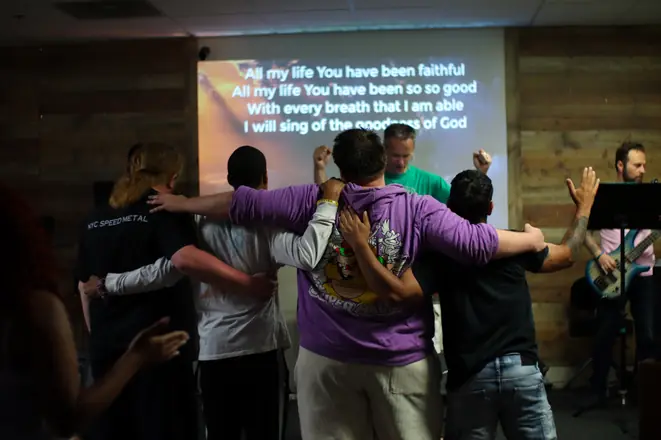Matheteuo Ministries congregation standing arm in arm during worship