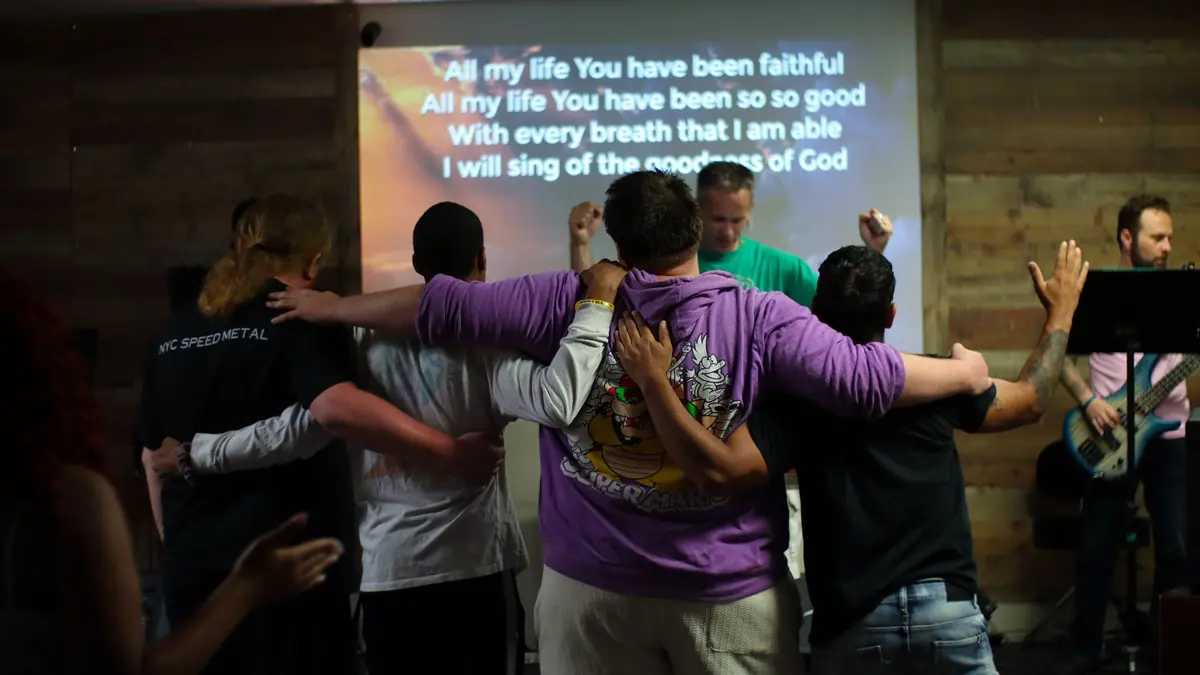 Matheteuo Ministries congregation standing arm in arm during worship
