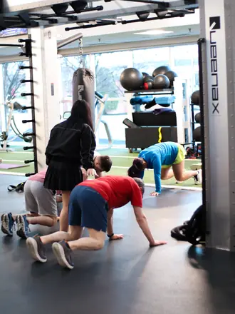 PowerHaus Fitness group class doing bear crawls across the turf